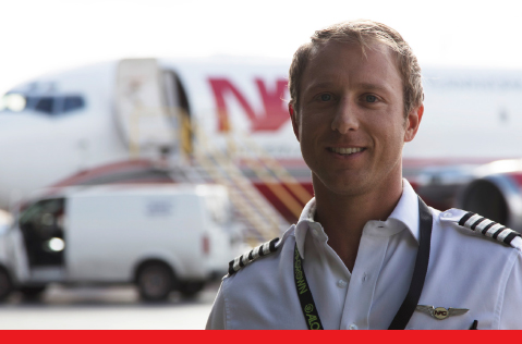 A Northern Air Cargo pilot standing in front of a NAC plane in the distance. 